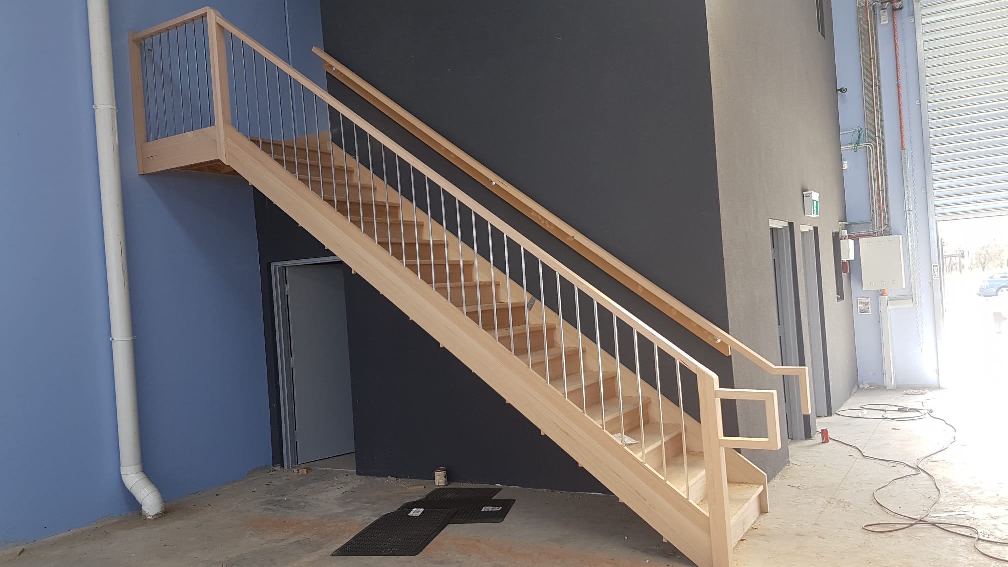 Commercial timber staircase and landing installed in a high-ceiling space