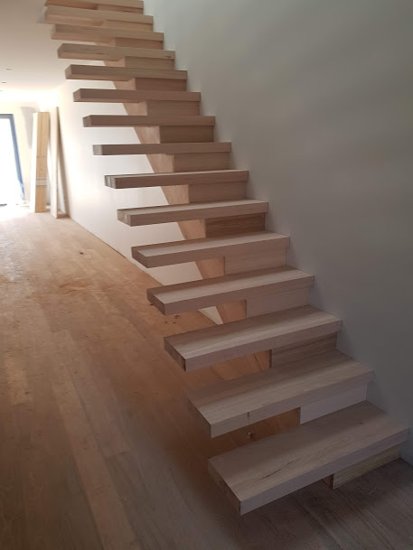 Floating timber staircase with open risers in a sunlit interior