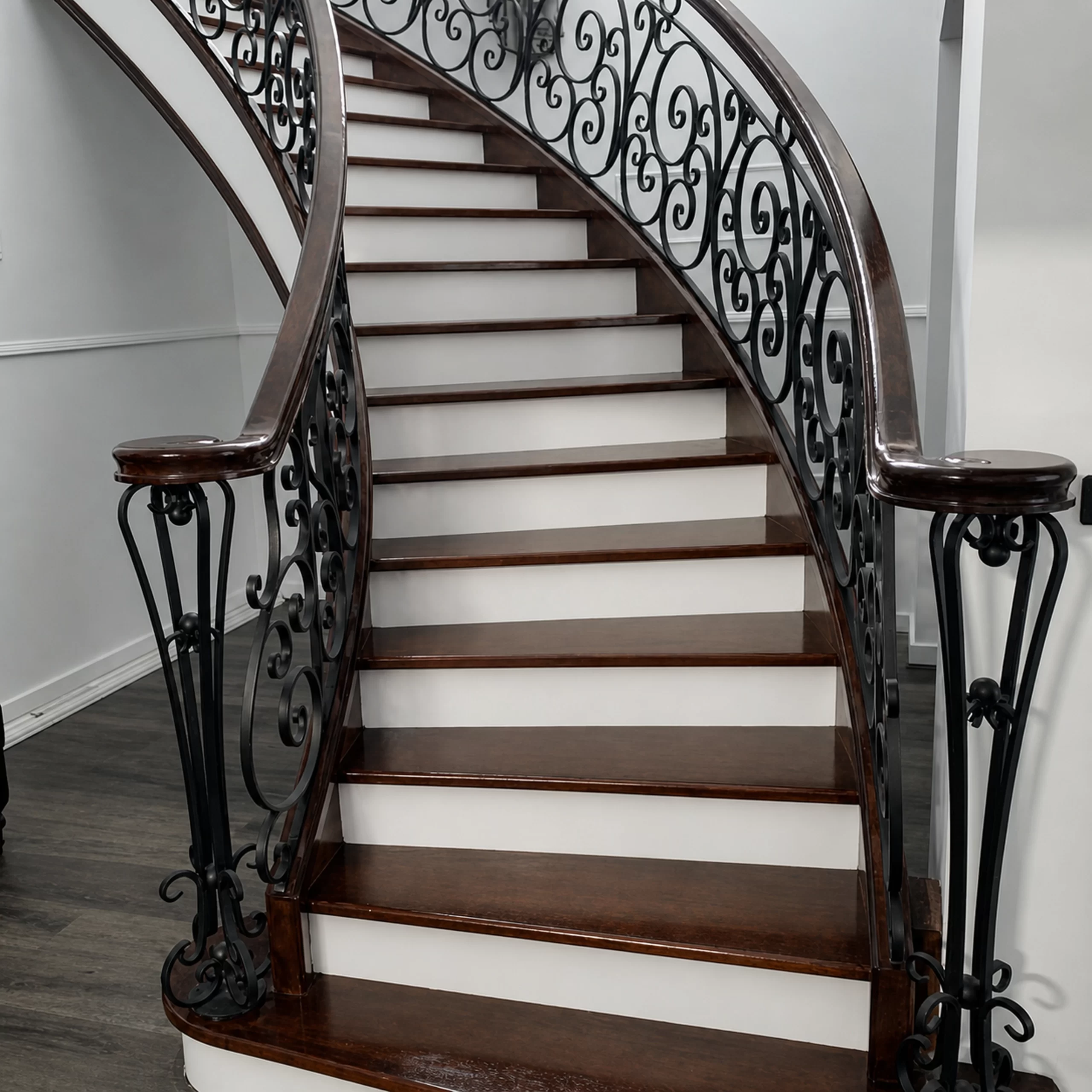 Curved timber staircase with ornate black lacework balustrade