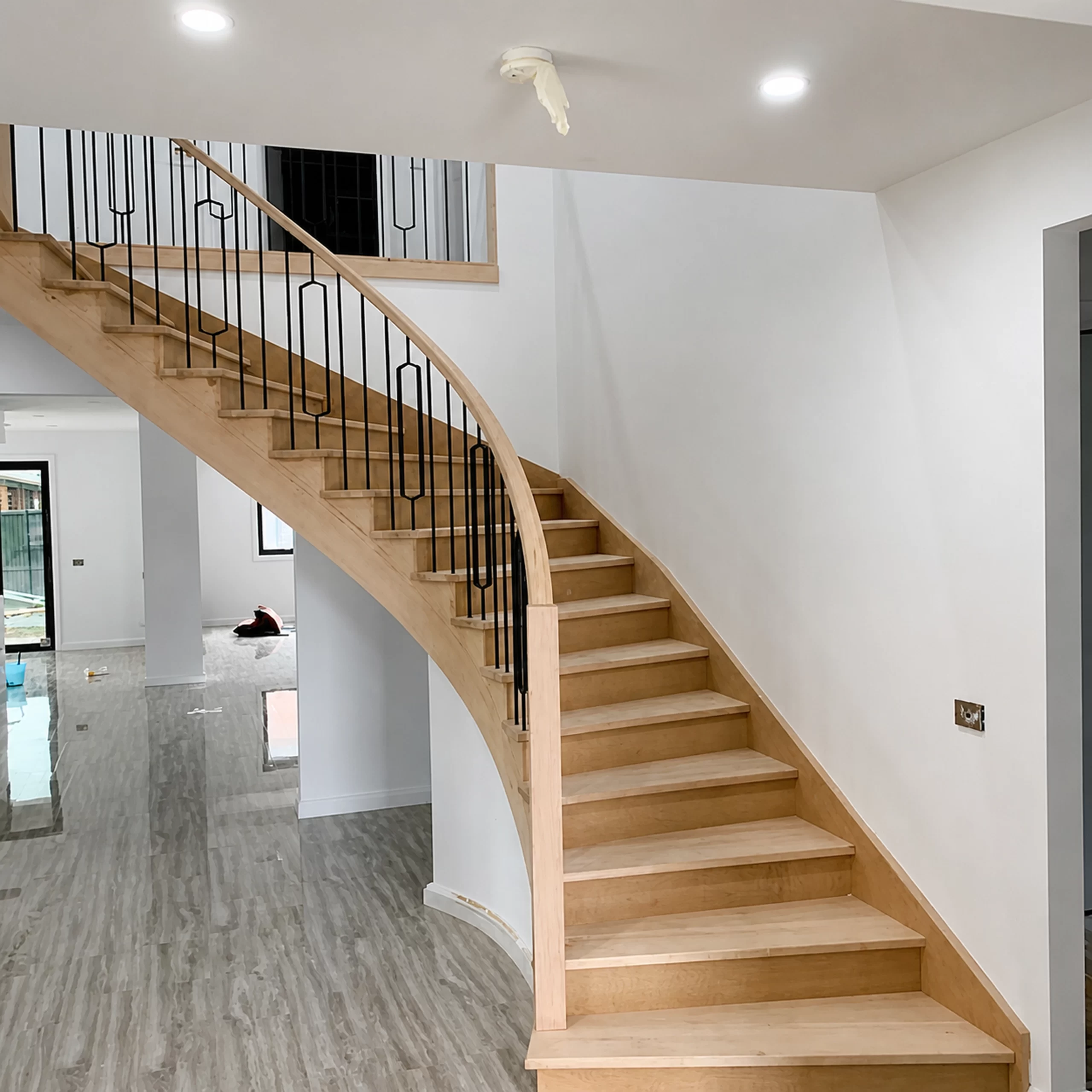 Curved geometric timber staircase in a bright interior by Planet Stairs