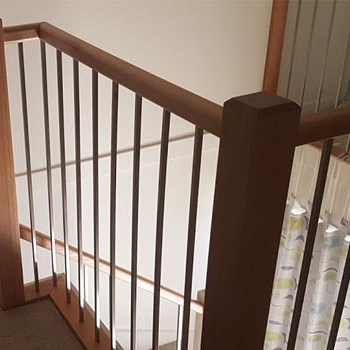 Timber stair balustrade with dark handrail and vertical metal spindles